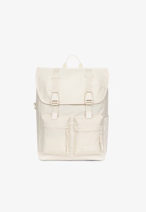 Prostokątny kremowy plecak z klapką, dwoma przednimi kieszeniami na suwak, paskami z klamrami i górnym uchwytem na białym tle.