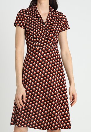Sukienka z krótkim rękawem w geometryczne wzory w kolorach czerwonym, czarnym i kremowym. Materiał jest gładki, z dopasowaną górą i rozkloszowanym dołem.