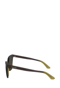 Ochelari de soare din plastic maro cu lentile închise. Rame rectangulare subțiri și brațe conice cu un accent galben și logo pe lateral.
