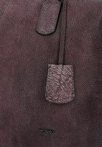 Bolso de mano texturizado en púrpura con un bolsillo de solapa y un detalle cosido. Cuenta con un logo negro en la parte inferior. El material parece similar al cuero.