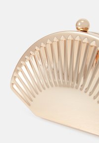 Metallic gold clutch with a fan-shaped design featuring vertical ridges and a rounded clasp. Smooth texture with a shiny finish.