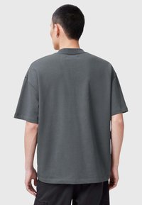 Mörkgrå oversized t-shirt med korta ärmar, ribbad textur, rund halsringning och rak nederkant. Inga synliga mönster eller accenter.