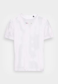 Bílý síťovaný tričko s krátkým rukávem, s kulatým výstřihem. Text "Tohle je láska" v barevných písmenech na zadní straně a logo na krku.