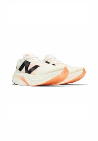 White running shoes with black accents and an orange outsole. Features a textured upper with prominent branding and a cushioned sole design.