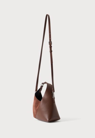 Sac à bandoulière en cuir marron avec une longue bandoulière ajustable, des fermoirs argentés et un panneau latéral en daim, présenté sur un fond uni.