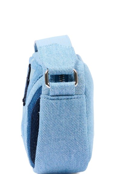 Petit sac à main en tissu denim bleu clair avec une boucle en métal argenté et des détails cousus, vu de côté.