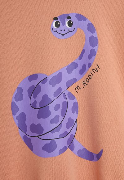 Light orange fabric featuring a purple cartoon snake with black spots, smiling expression, and stylized design, signed "M.Rodini."