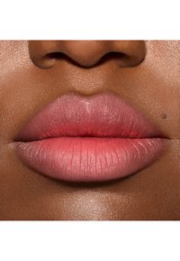 Close-up van lippen met een verloop van zachtroze naar koraal. Gladde textuur, subtiele glans en een duidelijke contour. Natuurlijke huidtint als achtergrond.