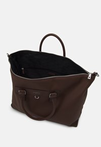 Sac fourre-tout synthétique marron avec doubles poignées, fermeture éclair sur le dessus et logo visible. L'intérieur présente une doublure noire à motif et une poche.