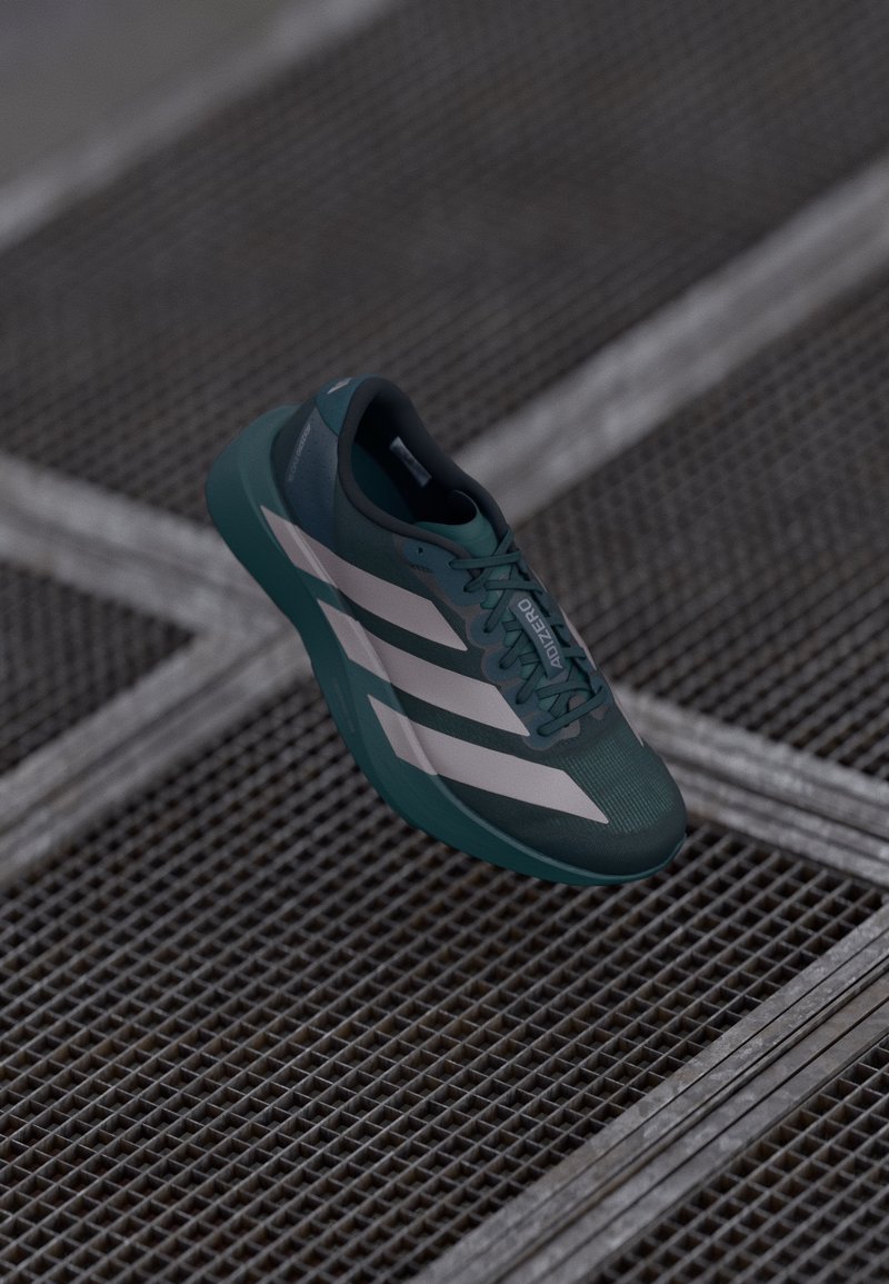 Chaussure de sport bleu foncé avec une tige texturée, arborant trois rayures blanches, un bout arrondi et une semelle rembourrée.