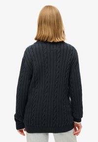 Granatowy sweter z grubym splotem o teksturowanym wzorze, z długimi rękawami, ściągaczem na dole i mankietach, o luźnym, wygodnym kroju.