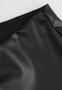 Czarna tkanina z sztucznej skóry o fakturowanej powierzchni i delikatnym połysku, z siateczkowym pasem wzdłuż górnej krawędzi.