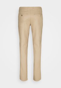 Beige slim-fit-housut nähtynä takaa, joissa on vyölenkit ja kaksi napitettavaa takataskua.