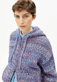 Gestrickter Hoodie in Blau- und Lilatönen mit einem strukturierten Muster, ausgestattet mit einem Reißverschluss vorne und einer Kapuze mit Kordelzug.