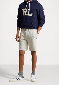 Námořnická mikina s krémovým logem "RL", šedé šortky, bílé tenisky s námořnickými akcenty a šedé ponožky. Ležérní oblečení s měkkými texturami.