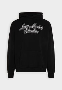 Sweat à capuche noir en tissu doux avec une poche frontale, des manches côtelées et un logo brodé "Low Lights Studios" en argent.