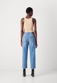Lys beige tank topp kombinert med blå rette jeans med et subtilt vertikalt mønster og fire lommer. Svarte ankelboots fullfører antrekket.