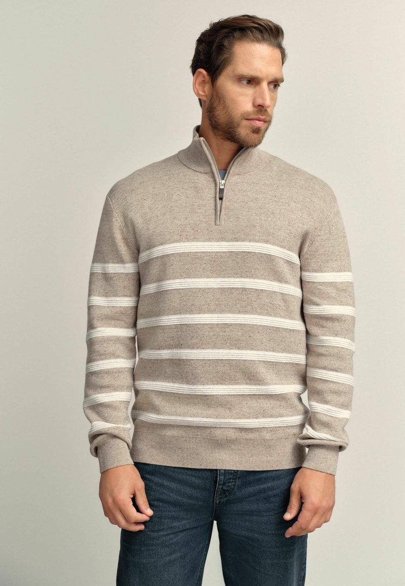 Beige Zip-Pullover mit weißen horizontalen Streifen, aus Strickstoff gefertigt. Figurbetonter Schnitt mit gerippten Bündchen und Saum sowie einem hohen Kragen.