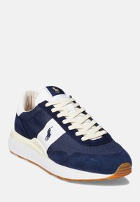 Mörkblå sneakers med vita accenter, i en blandning av mocka och tyg, rundad tå och snören i krämfärg. Gummisula med grepp.