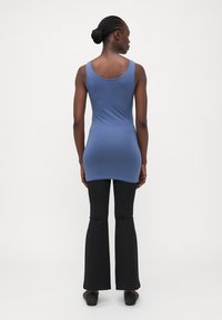 Blå tanktopp med en tettsittende design, kombinert med svarte vide bukser. Topp har en rund halslinje og en jevn tekstur.