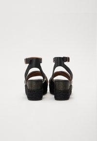 Schwarze Ledersandalen mit einem klobigen, strukturierten Absatz und einem Knöchelriemen. Glatte Oberfläche mit Ausschnittdesign und Schnallenverschluss.
