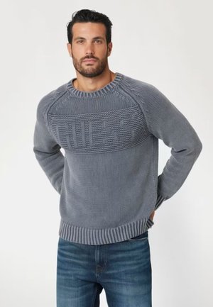 Maglione grigio lavorato a maglia con un design testurizzato, dotato di un colletto e orlo a coste. Accompagnato da un logo in evidenza sul petto.
