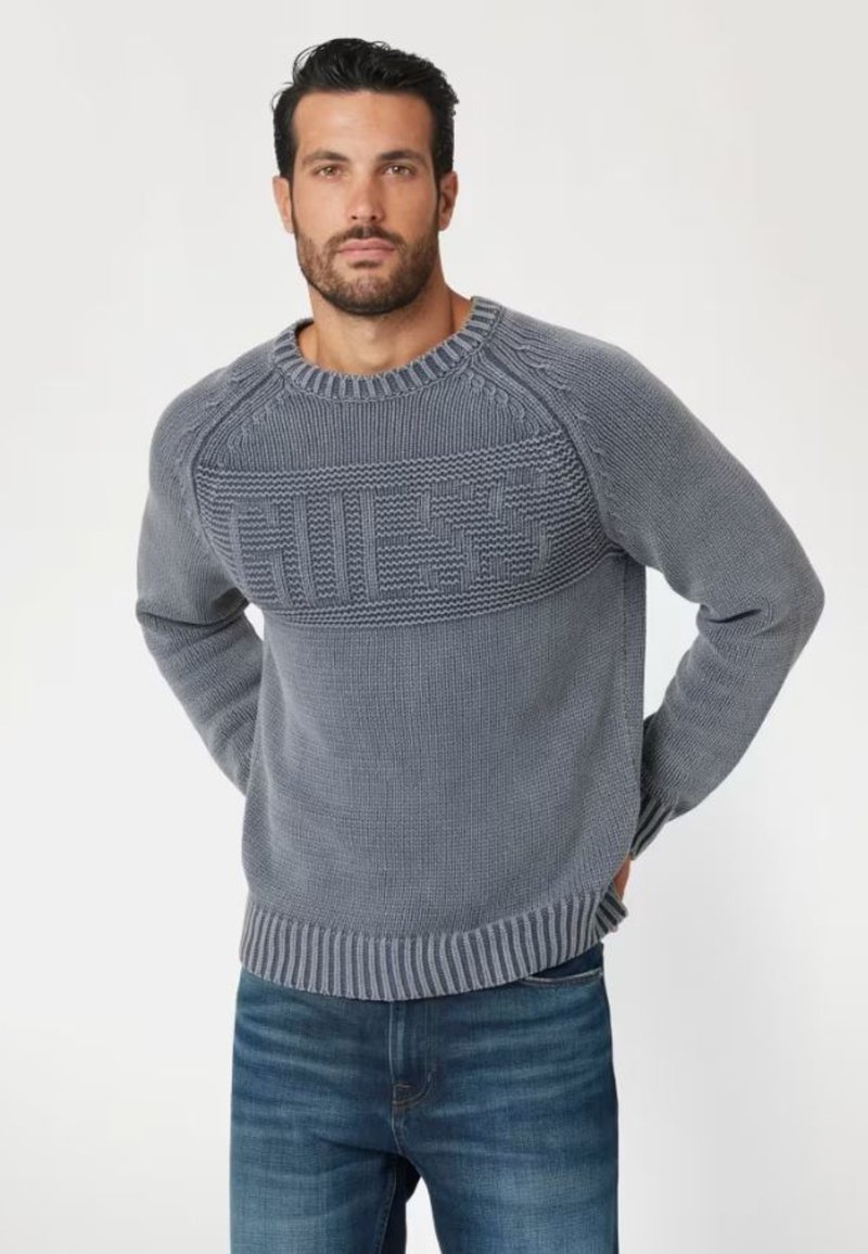 Maglione grigio lavorato a maglia con un design testurizzato, dotato di un colletto e orlo a coste. Accompagnato da un logo in evidenza sul petto.