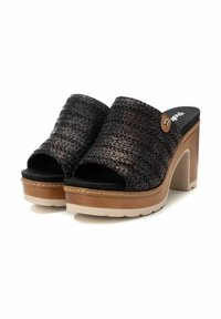 Sandalias de tira negras trenzadas con puntera cerrada y un tacón de plataforma grueso en tono camel. Presentan una textura suave y un sutil acento de logo en el lateral.