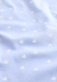 Light blue fabric with a soft texture and a repeating pattern of small white hearts throughout.