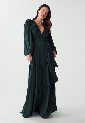 Dark green maxi dress made of soft fabric. Features long ruffled sleeves, a deep V-neck, and a tied waist with tiered bottom.