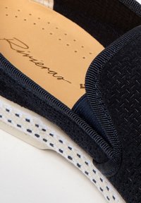 Chaussure bateau en marine à enfilage, avec tige en tissu texturé, col rembourré et semelle intérieure en beige. Semelle blanche avec coutures décoratives.