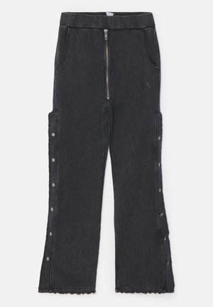 Schwarze Jogginghose mit strukturiertem Finish, ausgestattet mit einem Frontreißverschluss, Seitentaschen und Druckknopfdetails entlang der äußeren Naht.