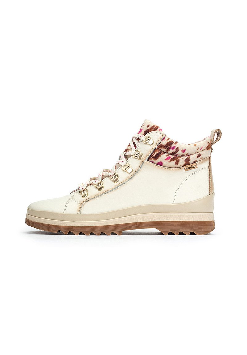 Botas altas de crema con herrajes dorados, cuello de piel sintética estampada y suela de goma texturizada. Presenta un frente con cordones y un diseño cosido.