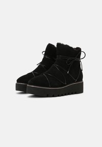 Bottines en suede noir avec un intérieur confortable, dotées de lacets croisés, d'une semelle épaisse et d'une surface texturée.