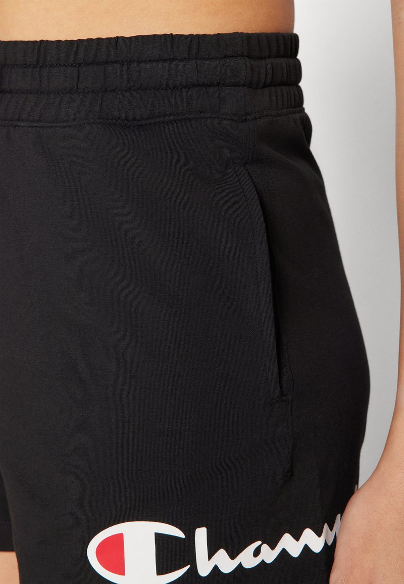 Shorts sportivi neri con una cintura testurizzata, tasca laterale e un dettaglio con logo bianco. Realizzati in materiale morbido ed elastico per il massimo comfort.