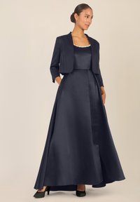 Abito in satin blu navy con un corpetto aderente e una gonna ampia, dotato di una giacca corta, dettagli in perle lungo il collo e tasche.