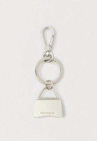 Breloc metalic argintiu cu un charm în formă de geantă mică gravat cu textul "COCCINELLE" și un carlig de homar pe un fundal alb.