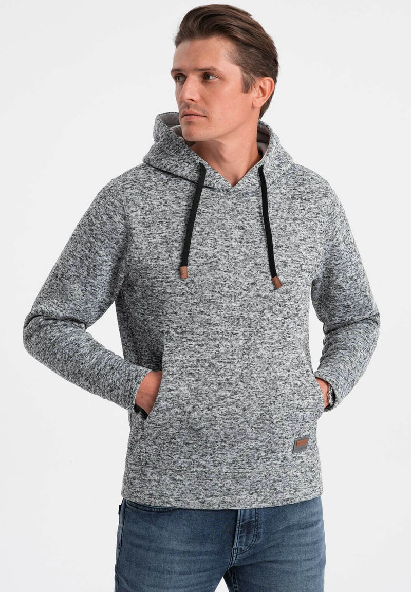 Sudadera gris jaspeada con un bolsillo canguro delantero, cordones negros y una tela texturizada. Presenta puños acanalados y un corte relajado.