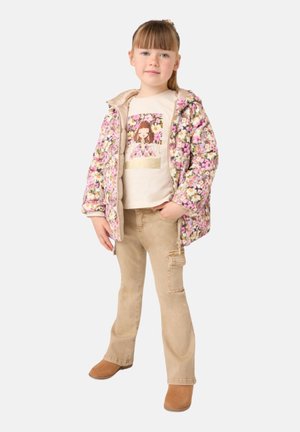 Giacca trapuntata floreale in rosa e giallo, t-shirt beige con grafica, pantaloni cargo marrone chiaro e stivali alla caviglia marroni. Tessuti dalla trama morbida.