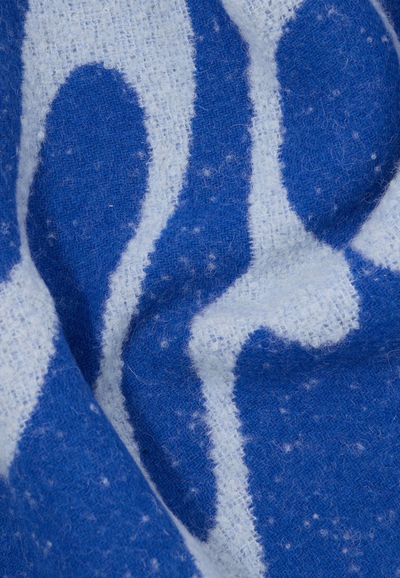 Blau-weißer Stoff mit einem weichen, strukturierten Oberflächen. Enthält wellenförmige Muster und hat ein leicht fusseliges Aussehen.