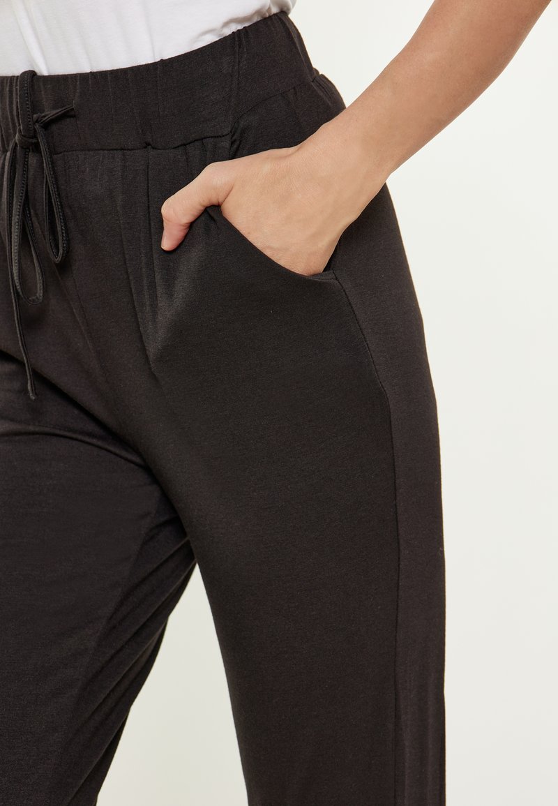 Zwarte joggingbroeken van een zacht materiaal, met een elastische tailleband met trekkoord, zijzakken en een slim fit ontwerp.