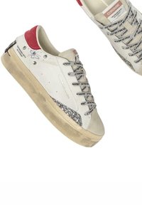 Sneaker bianche con finitura testurizzata, dettagli in glitter grigio e inserto rosso sul tallone. Presentano chiusura con lacci, lacci brandizzati e suola in gomma.