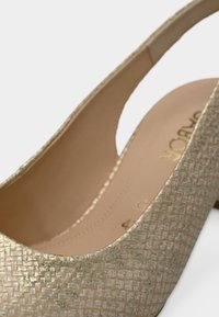 Χρυσό υποδήμα με σλιγκμπακ και υφή, με λείο εσωτερικό, που διαθέτει εξωτερικό με τετράγωνο μοτίβο και χαμηλό τακούνι.