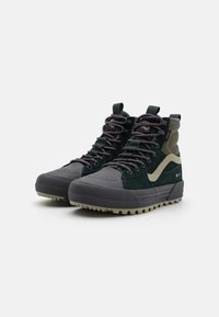 Zapatillas altas con ante y caucho en tonos verde oscuro y gris, puntera texturizada, cordones multicolores y una lengüeta en el collar.