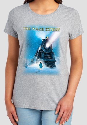 Child in blue coat stands facing a large steam train emitting light and snow, under the text "THE POLAR EXPRESS" on a gray shirt.