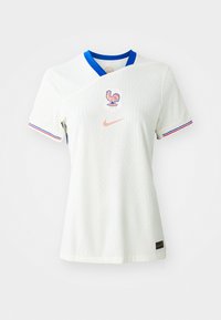 Maglietta da calcio bianca con colletto blu, texture a costine, presenta un emblema del gallo e il logo Nike in pesca, accentuata da strisce tricolori francesi sulle maniche.