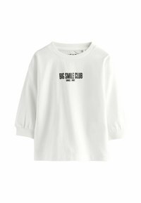 White cotton sweatshirt with puffed sleeves, crew neckline, and "BIG SMILE CLUB SINCE 1982" printed in black on the front.