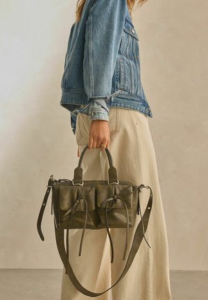 Kleine donkergroene leren tas met twee voorkruimels, gestrikt accent, afgeronde handvatten en een verstelbare schouderband.