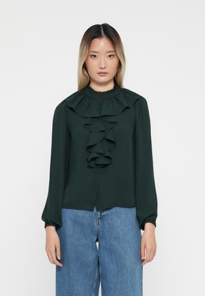Mørkegrønn bluse med høy volangkrage, frontvolanger og lange, rynkete ermer. Stoffet ser glatt ut med en subtil glans.