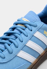 Blue suede sneaker with white stripes, textured laces, and gold accent on the side. Features a rubber sole for traction.